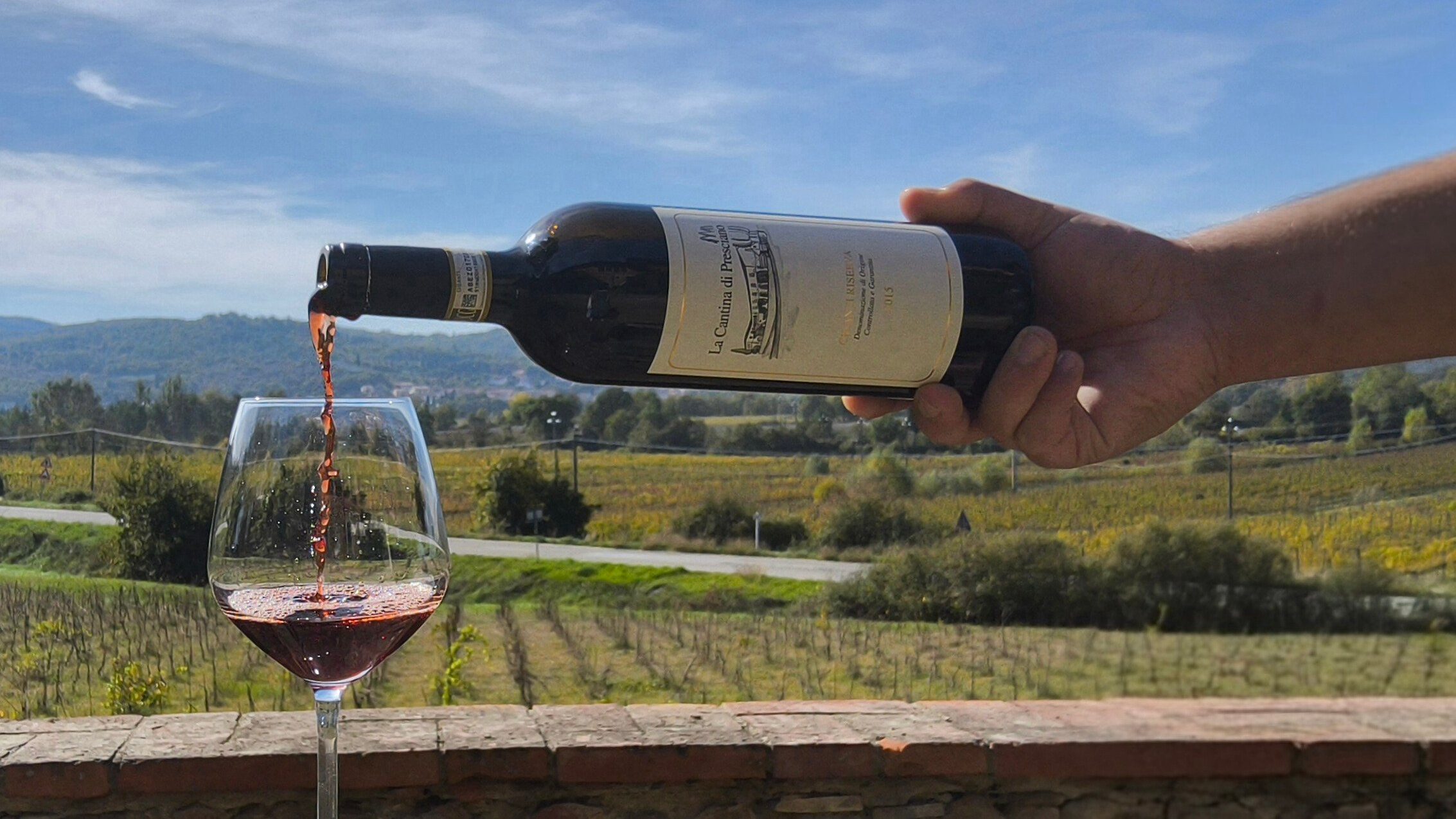 Il Chianti Riserva versato in un calice davanti alle vigne di Presciano